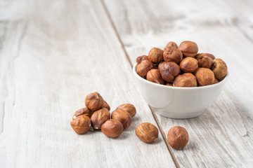 Hazelnuts in the white bowl on wood table