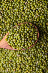 Scattered mung bean. Eco spoon. Mung bean, green moong in a wooden spoon, on black metallic vintage background. Copy space. Black background. 