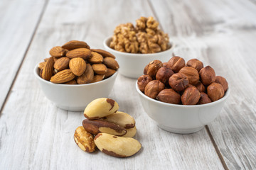 Different nuts in white bowls on wood table