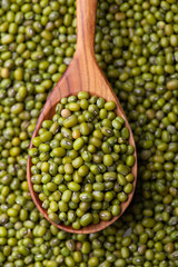 Scattered mung bean. Eco spoon. Mung bean, green moong in a wooden spoon, on black metallic vintage background. Copy space. Black background. 