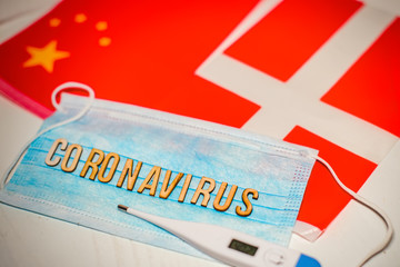 Novel Coronavirus outbreak concept. Coronavirus protective breathing mask and syringe over Chinese flag and flag of Denmark, Danish flag. 2019-nCoV virus infection originating in Wuhan, China