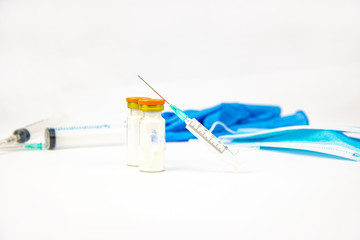 Medical syringe, antibiotic ampoule, gloves and a protective mask on a white background