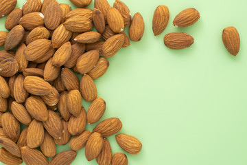 Scattered almond seeds on green background, stock photo.