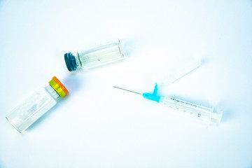 Medical syringe and yellow antibiotic ampoule on a white background