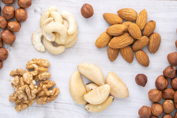 Different nuts piles on wooden table, stock photo.