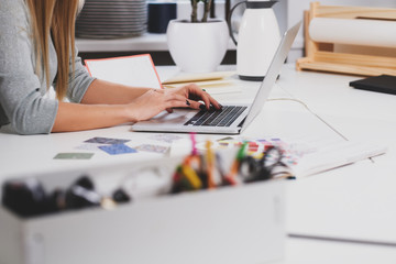 On the first plan there are box with accessories for office and girl with computer on the background.