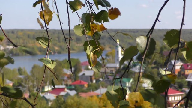 View of the old town and the church through the foliage of birch trees.