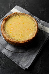 Healthy hygge style dessert. Lemon pie with wholegrain oatmeal crust on cooling rack and linen cloth on black background high angle view
