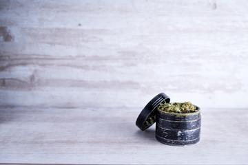 Recreational marijuana and metal grinder on a white stone background after Illinois passes a law to legalize weed sales and pardon weed related prisoners. Flower trichomes and kief dried during curing
