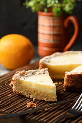 Healthy homemade gluten free dessert. Open lemon pie with wholegrain oatmeal crust on dark oak cutting board with mint and lemon on background