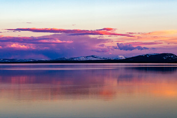 Beautiful sunset over Lake Yellowstone with reflection in water and snow capped mountains in the background
