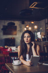 Business woman using tablet and drinking coffee in a cafe.