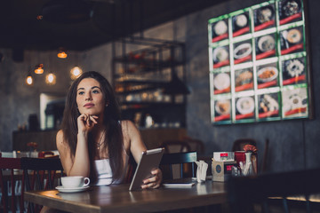 Business woman using tablet and drinking coffee in a cafe.