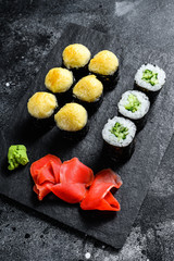 sushi rolls with cucumber, salmon and shrimp on a stone tray. Black background. Top view