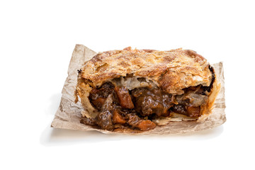 Puff pastry steak pie on baking paper isolated on white