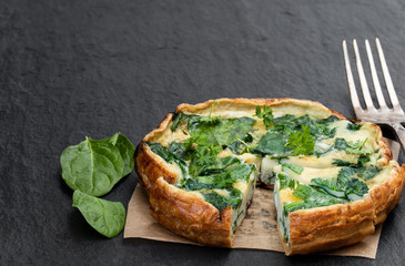 Omelette with spinach on black stone background