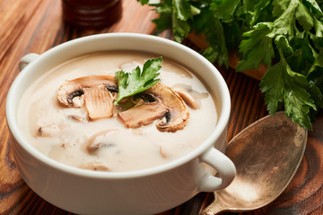 Bowl of mushroom soup with parsley on a wooden table