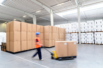Arbeiter in Sicherheitskleidung mit Helm und Warnweste arbeitet im Warenlager einer Spedition //...