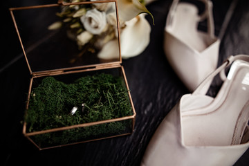 Wedding bouquet of white flowers with a pair of wedding rings and shoes lie on a gray background on a summer wedding day