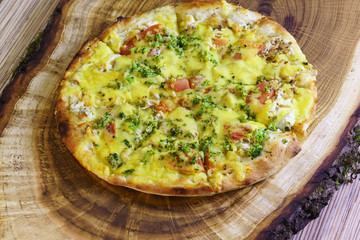 Vegetarian pizza with tomatoes, broccoli and cheese on a wooden stand. Selective focus