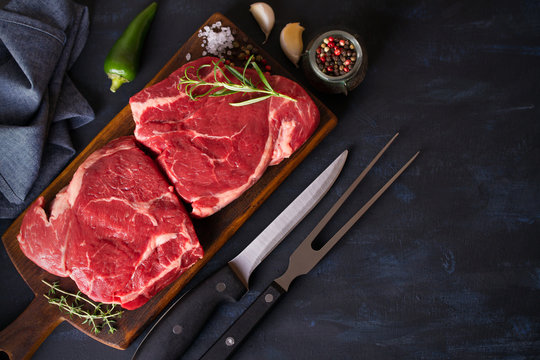 Raw fresh meat, beef steak fillet on wood chopping board, dark background. Overhead, flat lay image