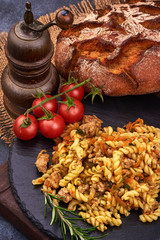 Fusilli pasta with minced meat on rustic background