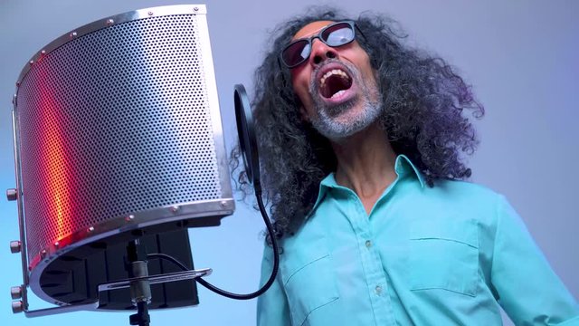 Middle aged american man in sunglasses is singing at the studio emotional song.