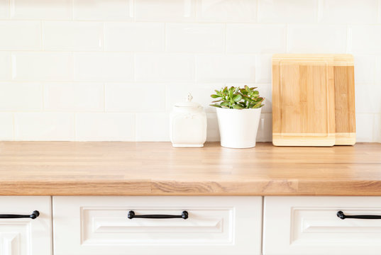 Bright And Clean Kitchen With White Cabinets, Close Up. Cutting Boards, Green Succulent Pot On A Wooden Worktop. Kitchenware In Modern Kitchen Interior. White Tiles Background