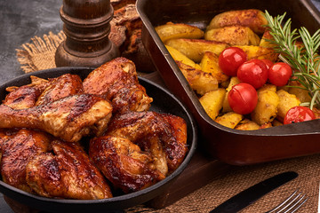 Delicious Roasted chicken wings with baked potatoes on rustic background