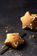 Handmade custard gingerbread in the shape of a star on a black background. Homemade baking. Board made of stone. Baking crumbs.