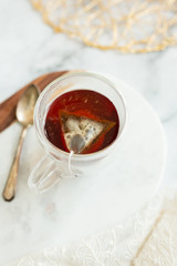 Black tea steeping in clear mug on marble