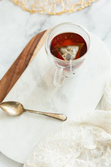 Black tea steeping in clear mug on marble