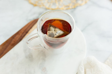 Black tea steeping in clear mug on marble