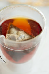 Black tea steeping in clear mug on marble