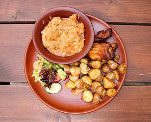 Grilled piece of pork, fried potatoes and stewed cabbage on a ceramic plate