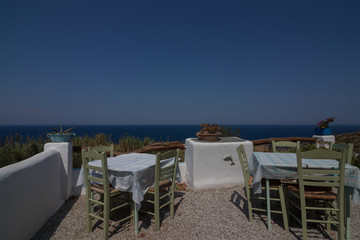 typical Greek tavern with inviting tables on the terrace with romantic view to the Aegean Sea 