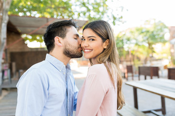 Man Kissing Happy Girlfriend Outside Cafe