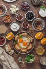 Fototapeta na wymiar Delicious turkish breakfast with eggs, olives, cheese, cucumbers, jam and yoghurt, flat lay