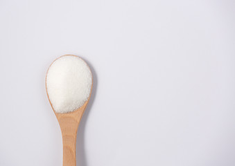 Brown sugar in a wooden spoon on a white background, healthy sugar. Used for cooking or desserts.