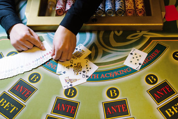dealer shuffles the poker cards behind gambling table in a casino, close up view