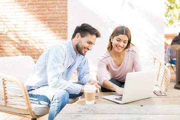 Happy Couple Is Using Laptop At Cafe