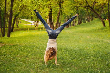 Girl makes an acrobatic wheel. On the grass.