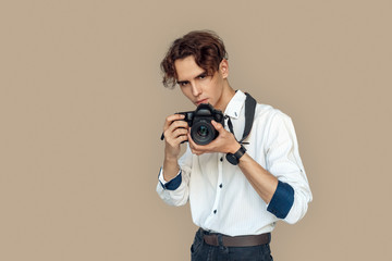 Obraz premium Freestyle. Stylish photographer standing isolated on gray taking photo on camera pensive