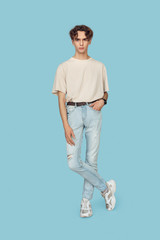 Fototapeta premium Freestyle. Man standing isolated on gray crossed legs hand in pocket pensive