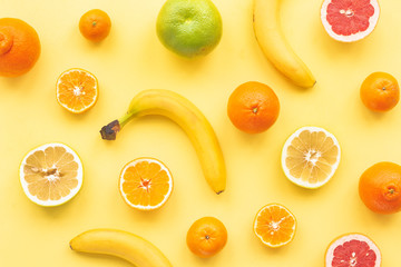Fresh citrus fruit, banana on yelllow background, flat lay, top view
