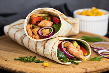 Burritos wraps with chicken and vegetables on dark background. Mexican food