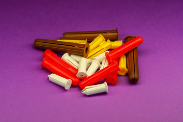 Dowels of different different colors on a lilac background.