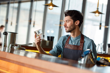 Professional Occupation. Bartender standing at counter looking at glass dreamful