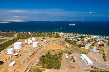 Fototapeta na wymiar Aerial view of petrolium processing plant near a port, looking out to a bay, with cruise ship in distance