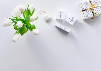 Valentines day geometric panoramic flat lay, top view on white background. Tulips, coffee cups and marshmallows, text space. Valentine gift wrapped in paper. Wood calendar with 14 February.